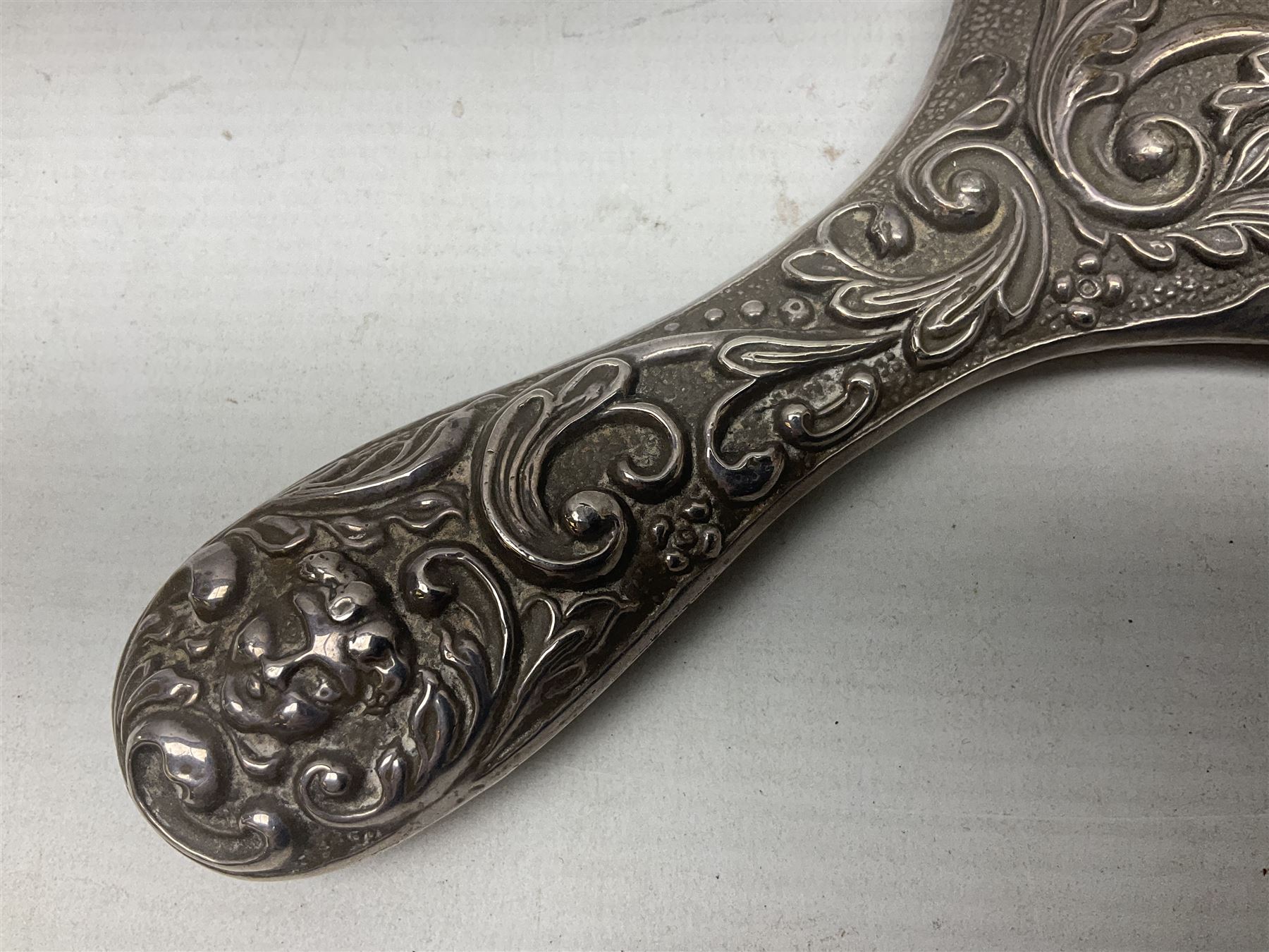 Silver mounted dressing table mirror, embossed with birds, masks, and foliate and C scrolls, hallmarked Birmingham, and fruit knife with mother of pearl handle and silver blade, (2)