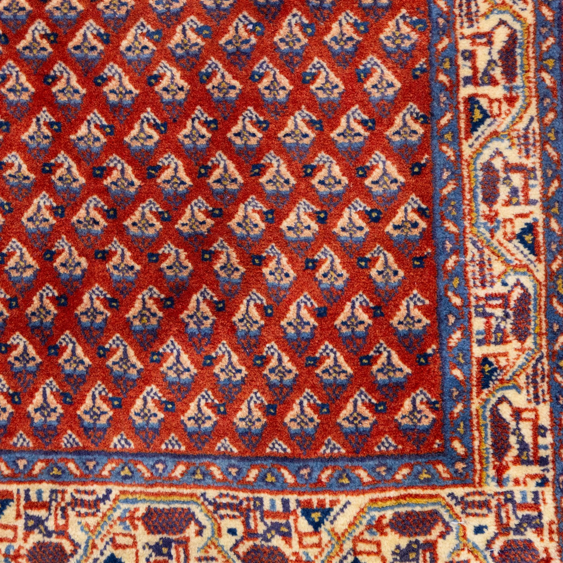 West Persian Saraband (Boteh-Mir) runner madder-red field densely decorated with repeating boteh motifs, arranged in diagonal rows enclosed by a geometric border of stylized motifs, between multiple guard stripes, cotton fringe ends  