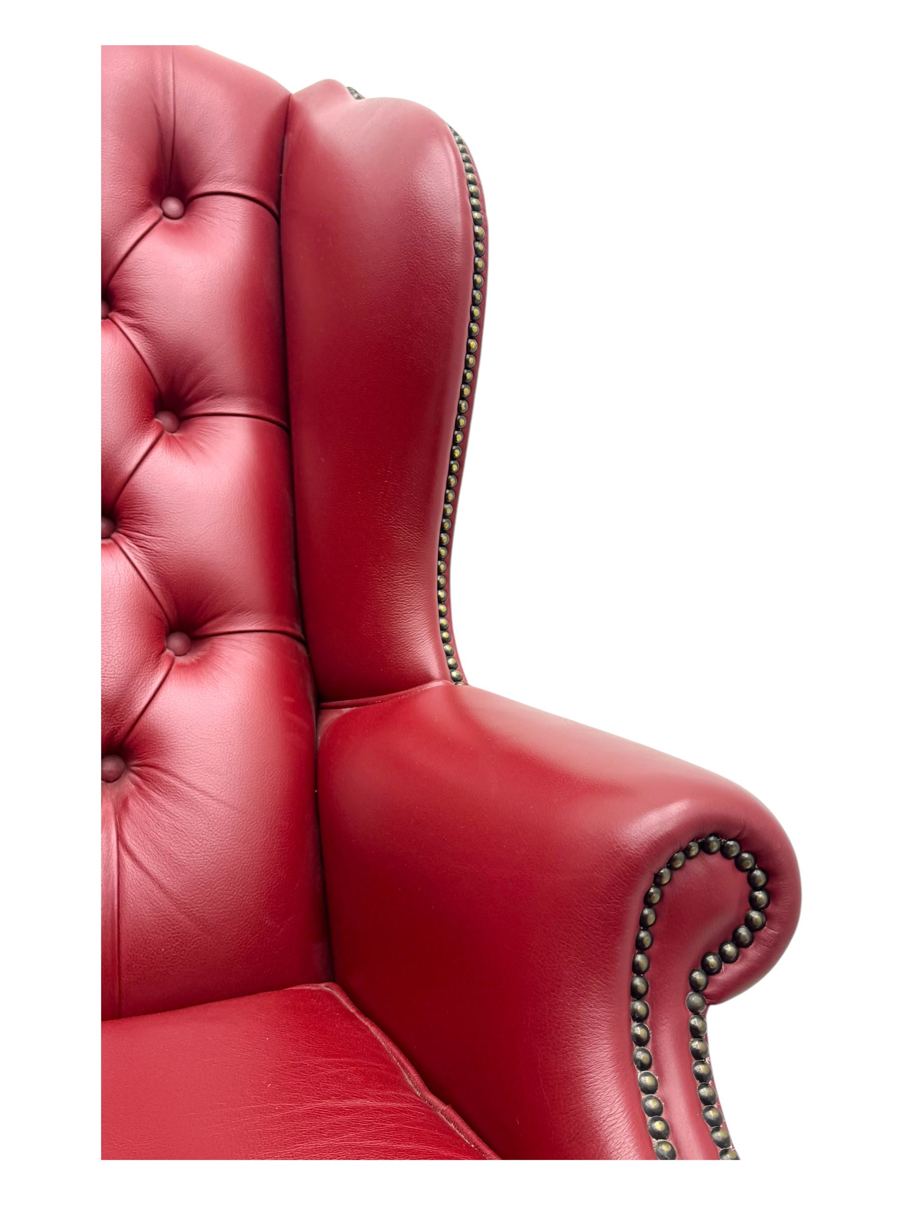 Kingsgate - contemporary 'Queen Anne' wingback armchair with matching stool, high back with deep button tufting, upholstered in red leather with brass stud trim, on carved cabriole supports