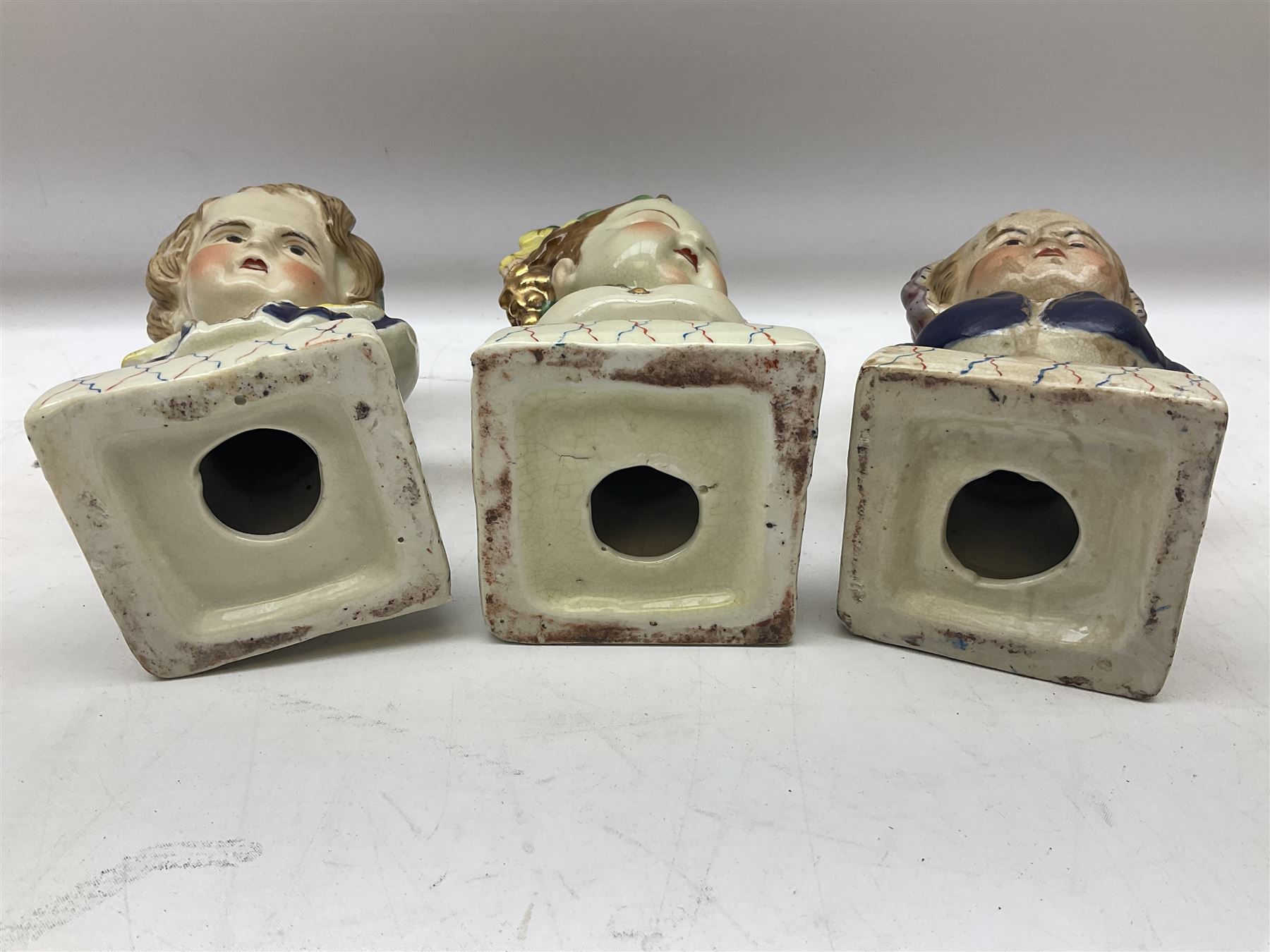 19th century pair of hand painted ceramic busts of children, together with a third similar example of a putti with a crown of ivy, tallest H23cm 