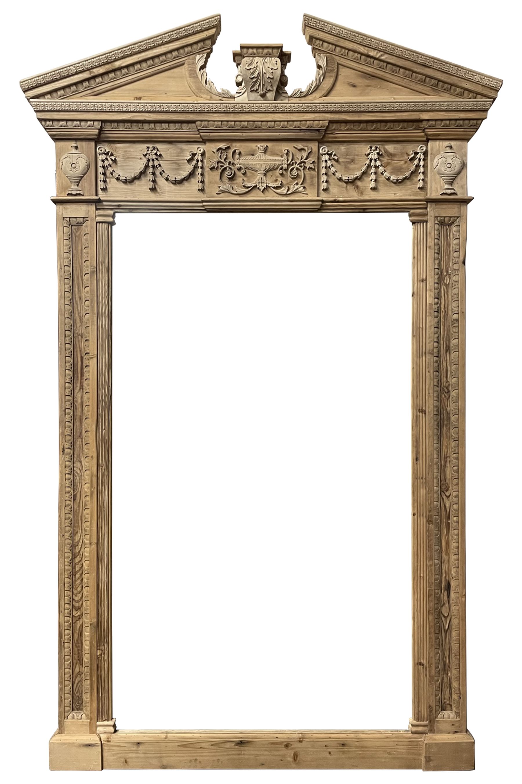 Large Adams design pine frame mirror, sloped broken arch pediment with central acanthus leaf carving, the frieze decorated with bell flower garlands and central kylix vase motif, large plain mirror plate flanked by panelled sides with egg and dart mouldings and reeded slip mouldings, on plinth base
