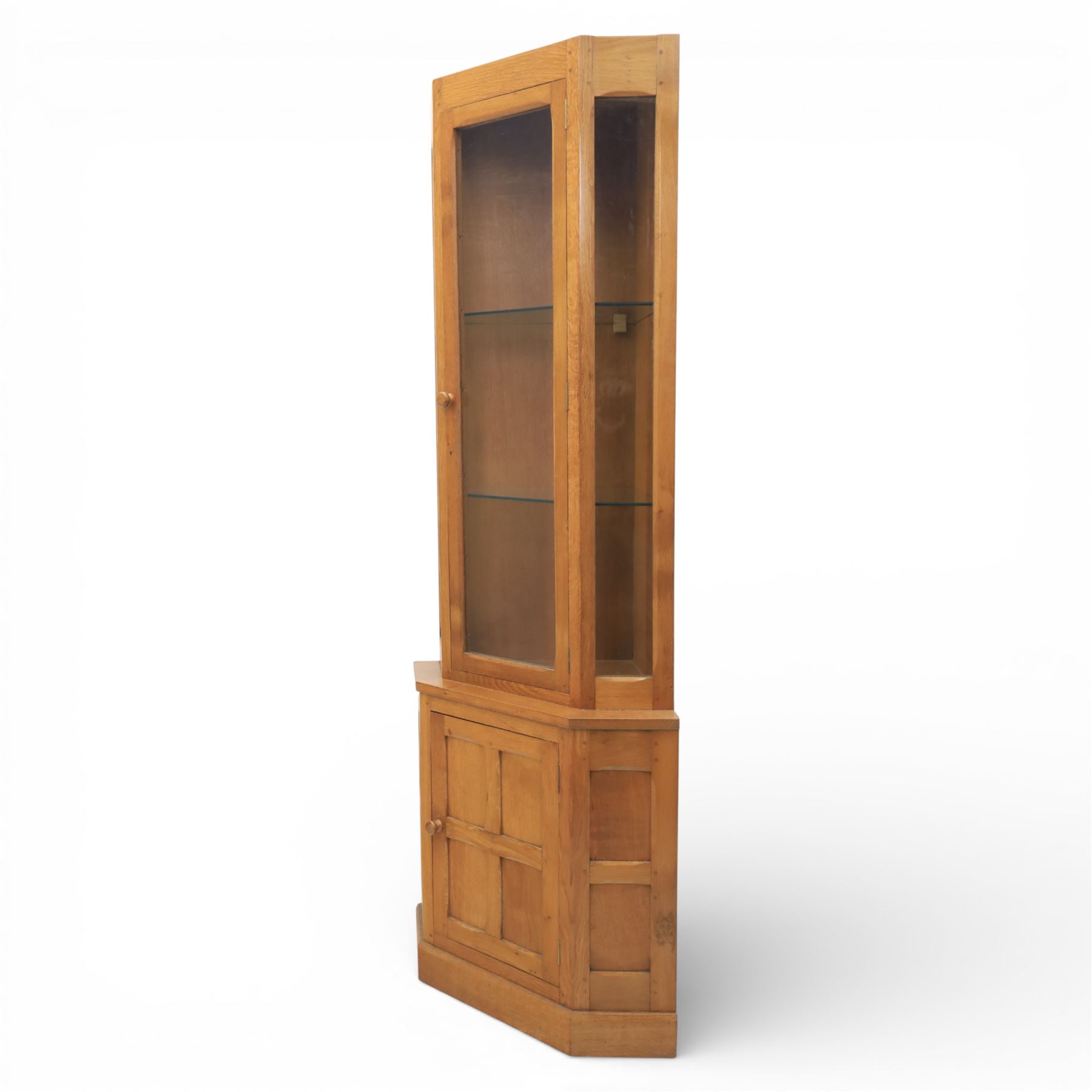 Cat & Mouseman - oak corner cabinet, glazed door with two fixed glass shelves, above a panelled door and sides raised on a plinth base, with cat and mouse carving to the lower side by Lyndon Hammell a former apprentice of Robert 'Mouseman' Thompson