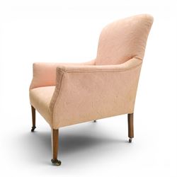 Edwardian mahogany framed armchair of traditional shape, high sprung back and seat over squared padded arms, upholstered in foliate patterned pale pink upholstery, on square tapering supports with brass castors