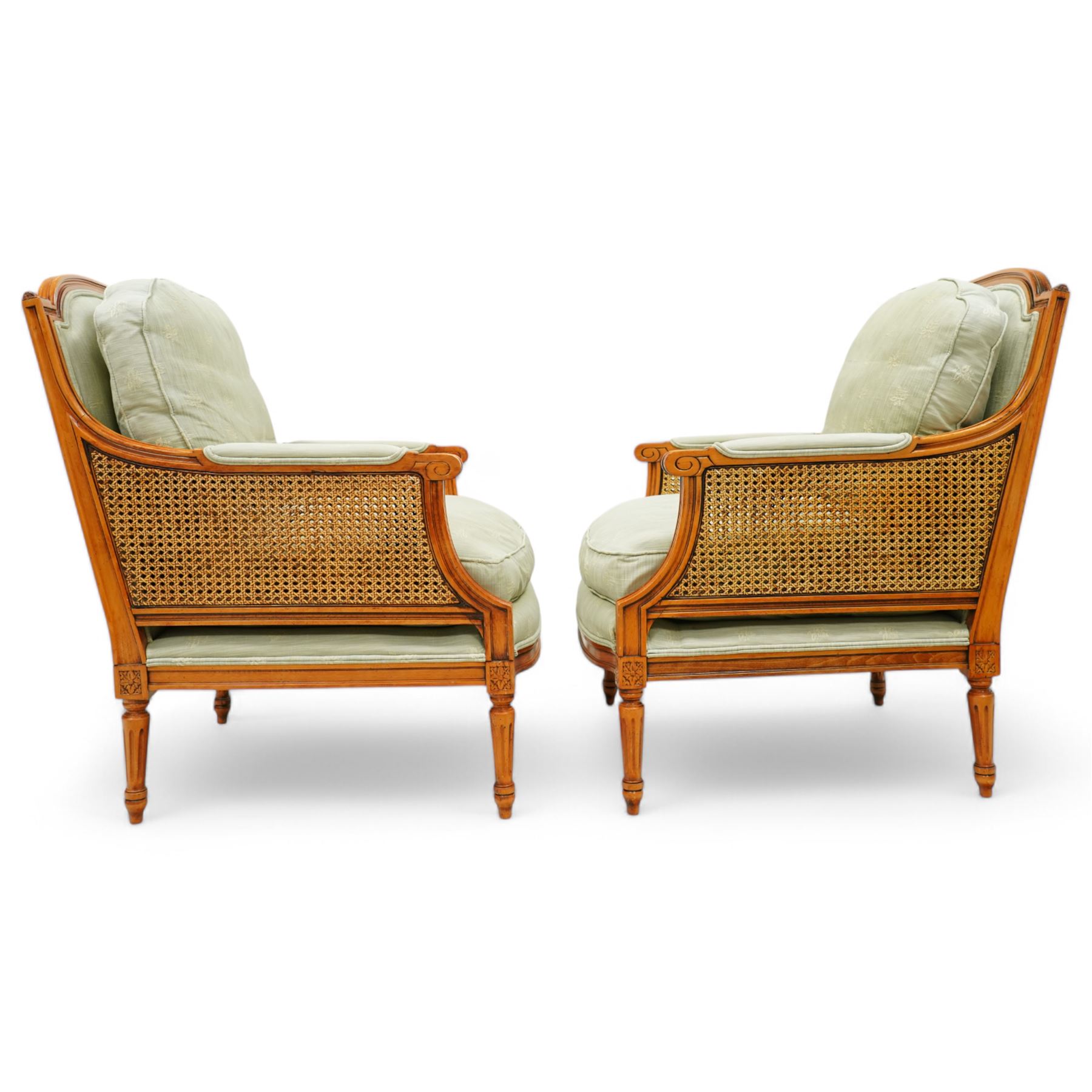 French Empire design varnished wood three piece lounge suite comprising of two cane armchairs and matching sofa, carved top rails with foliate terminals, cane side panels and padded scroll arms, upholstered in a green brocade with matching piping, on fluted legs