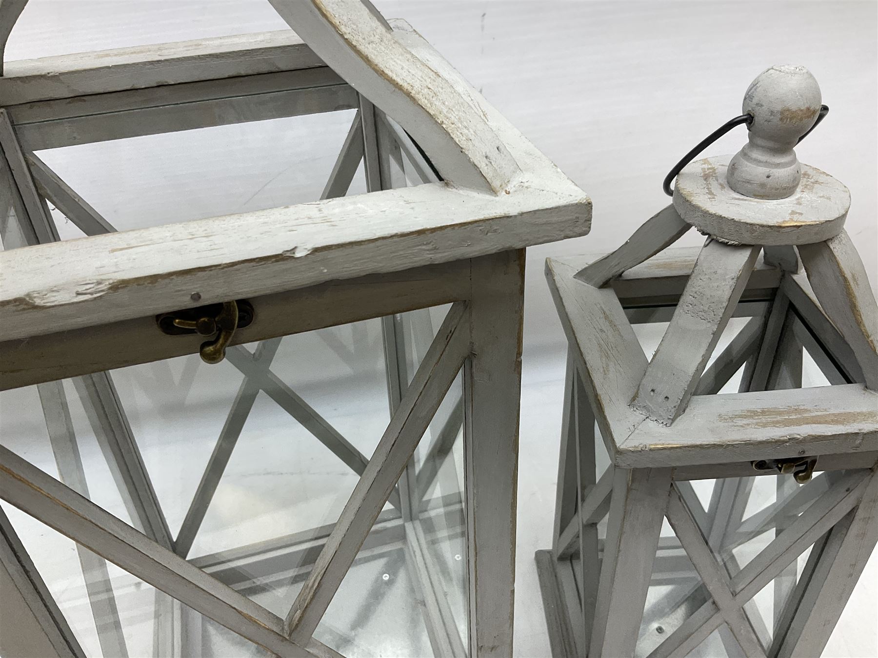 Two wooden lanterns with four glass sides, loop handles and open tops, largest example 58cm