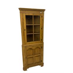 Traditional light oak corner cabinet, projecting cornice, dentil frieze, single glazed door above single fielded door