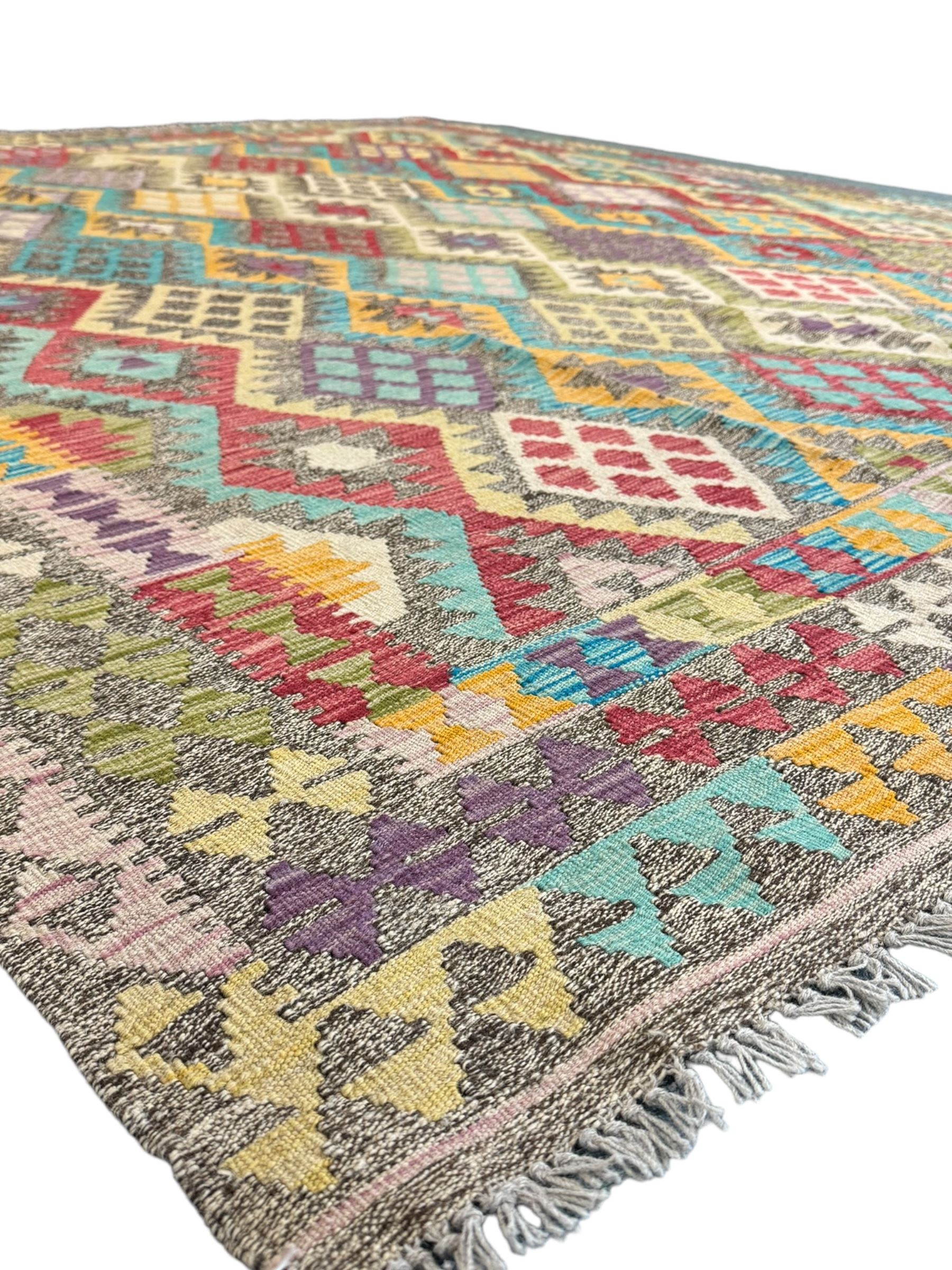 Anatolian Kilim cream ground rug, decorated with repeating diamond motifs in red, blue, yellow, and green, bordered by narrow bands of stylised geometric patterns in contrasting shades
