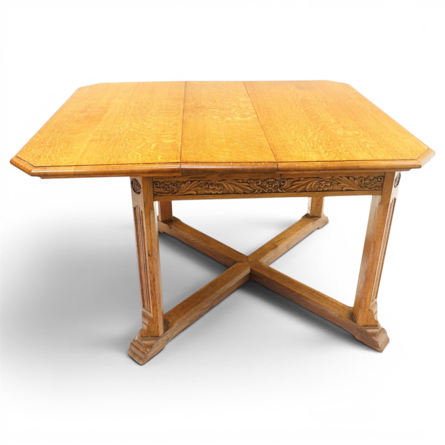 Waring & Gillow - Arts and Crafts oak draw-leaf extending dining table rectangular moulded top with chamfered corners, two additional leaves, carved frieze over fluted section supports, united by low X-shape stretchers
