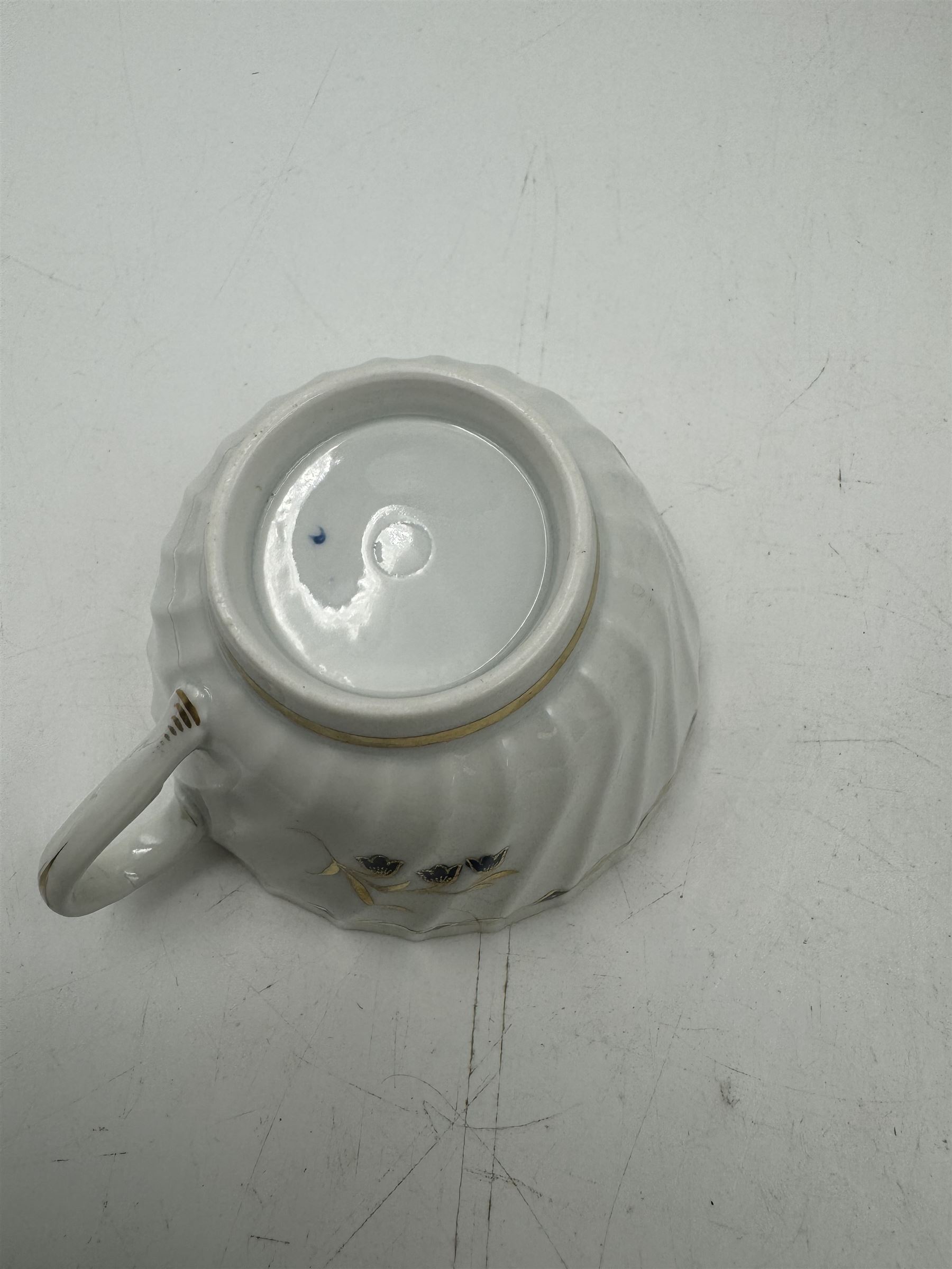 18th century Caughley blue and white sparrow jug, decorated in the Mother and Child pattern, circa 1780-1790, with underglaze C mark beneath, H9cm, together with a Worcester coffee cup, circa 1785 painted with floral sprays in underglaze blue and gilt, with crescent mark beneath, and a Caughley trio of tea cup, tea bowl and saucer, each of moulded wrythen fluted form and decorated with gilt and blue sprigs and bands, each with crescent mark beneath, (5)