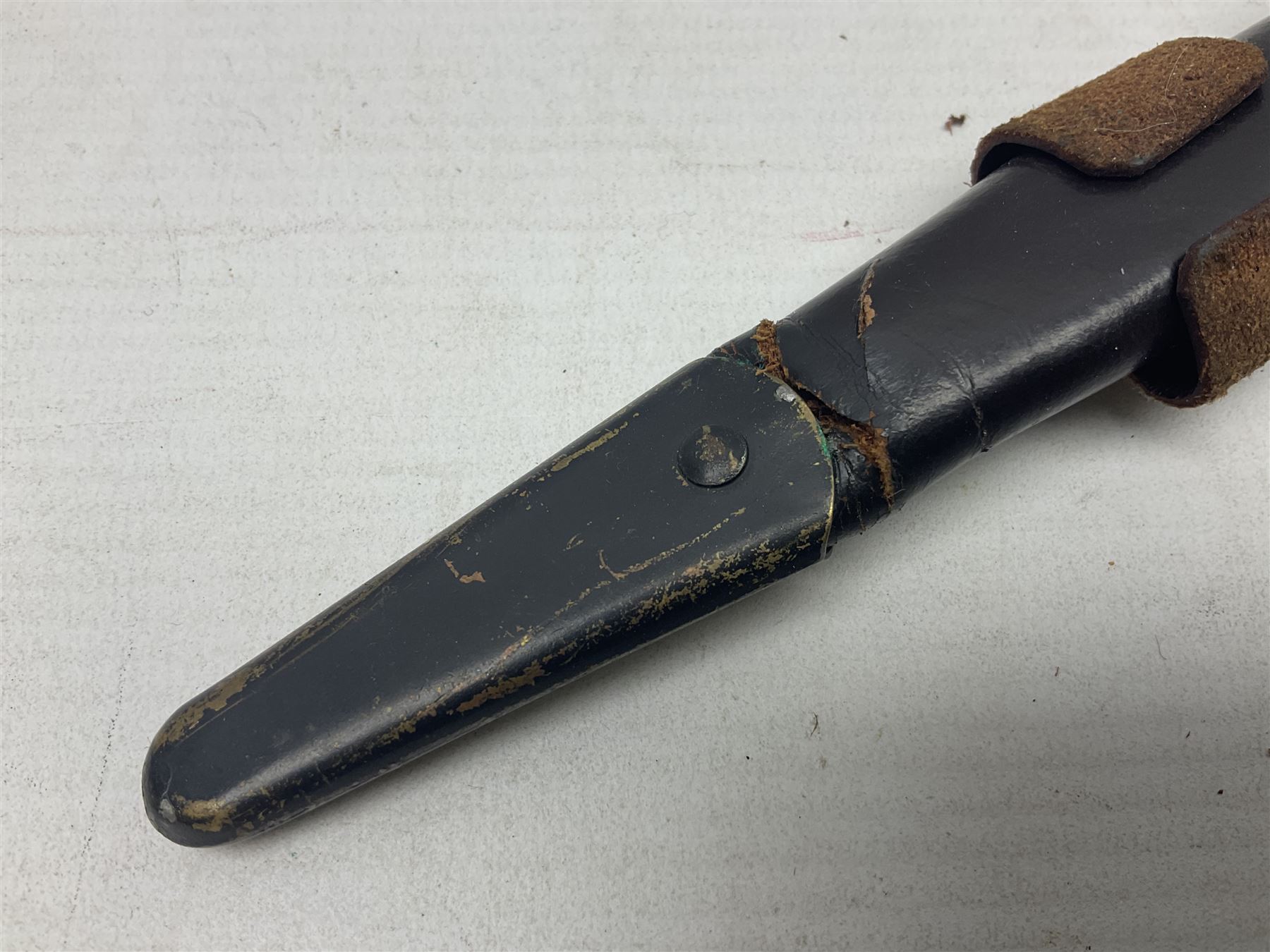 Third Pattern Commando Knife or Dagger with 17.5cm flattened diamond section blade and regulation black painted ribbed copper hilt with brass pommel nut; stamped William Rodgers Sheffield England to the cross-piece; in black painted brass mounted leather scabbard L34.5cm overall