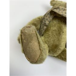 Early 20th century German Steiff teddy bear c1910 with wood wool filled humped back mohair body, swivel jointed head with black boot button eyes and horizontally stitched black nose and mouth, FF metal button to left ear, jointed elongated limbs with felt paw pads and black stitched claws H13