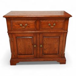 20th century country oak side cabinet, rectangular top over two short drawers and twin panelled cupboard doors, flanked by reeded uprights, on plinth base