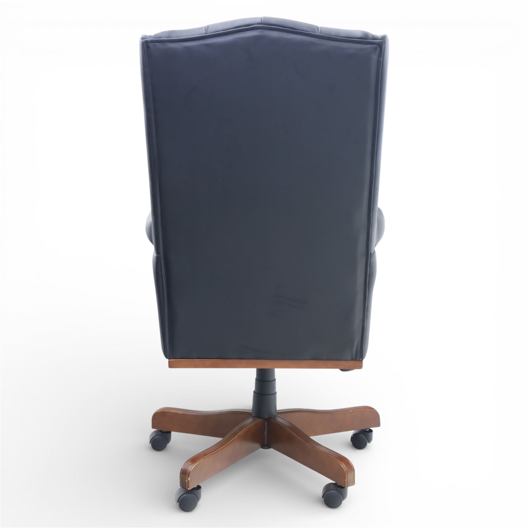 Chesterfield style desk chair upholstered in black, brass studded trim with tall button backed seat, with faux wooden base raised upon castors
