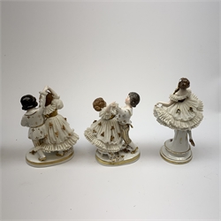 A 20th century Sitzendorf porcelain figurine, modelled in lace dress detailed with gilt flowers and raised upon a circular stepped base, with mark beneth, H19cm, together with a pair of similarly modelled 20th century Continental figure groups, probably Sitzendorf, each modelled as a boy and girl dancing, plus a urn hand painted with flowers and heightened with gilt, supported by allegorical figures (a/f). 
