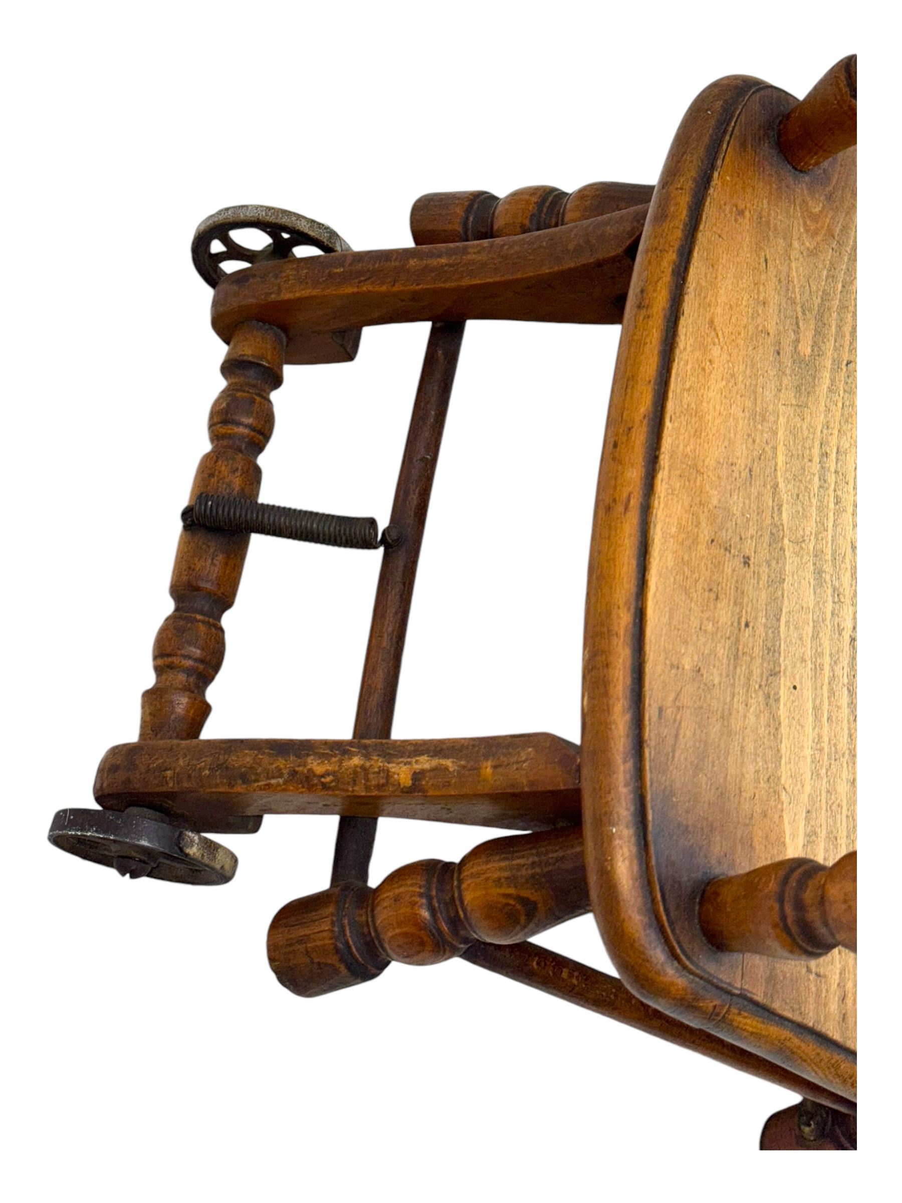 Late 19th century American oak child's metamorphic high chair and play table, carved spindle backrest with pierced splat, detachable tray with abacus and hand painted pastoral decoration, on turned supports with metal wheels
