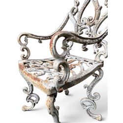 Pair of Victorian cast iron garden chairs, the ornate pierced back of scrolling foliate design, scrolling arm terminals over splayed supports formed of C and S-scrolls, in distressed white painted finish