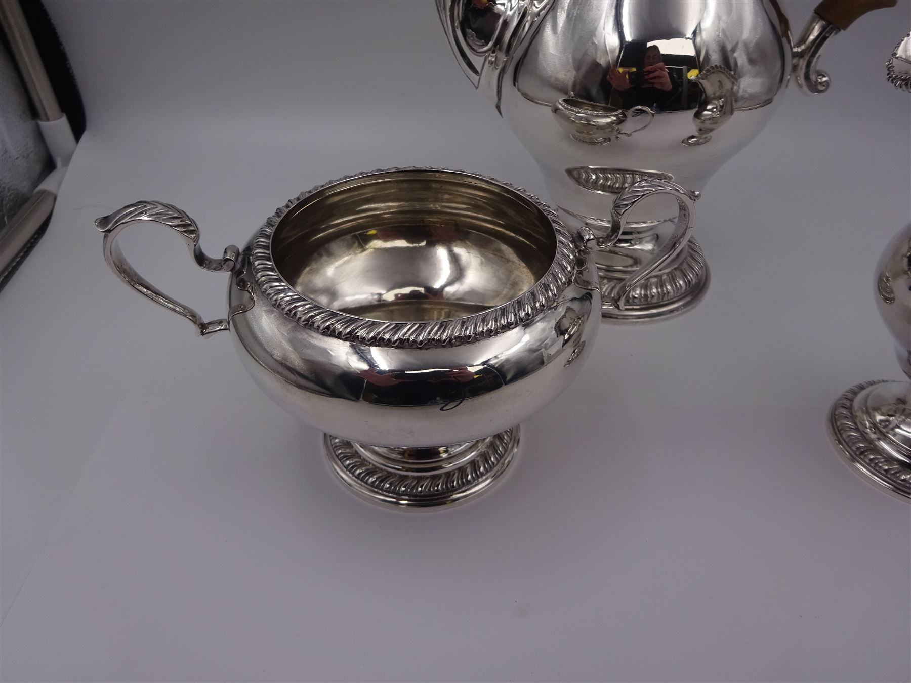 Mid 20th century three piece silver coffee service, comprising coffee pot, milk jug and twin handled open sucrier, of waisted form upon circular domed foot,  with oblique gadrooned rim, the milk jug and sucrier with acanthus capped handles, the coffee pot with wooden handle and finial, hallmarked William Comyns & Sons Ltd , London 1961, coffee pot H27.5cm