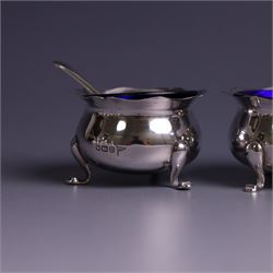 Early 20th Century four piece silver cruet set, comprising a pair of pepper shakers and a pair of open salts, each of circular form with shaped rims and upon three pad feet, hallmarked Walker & Hall, Sheffield 1912, the open salts with two silver plated salt spoons and blue glass liners 