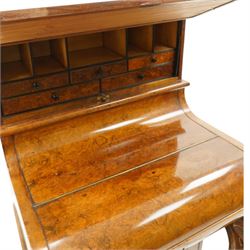 Victorian burr walnut piano-top Davenport, the raised rectangular superstructure with moulded cornice above a panelled fall-front enclosing drawers, the curved hinged writing slope opening to reveal a fitted interior above a sliding tooled leather writing surface, flanked by carved foliate scroll supports, the right side fitted with four drawers behind an arched panelled cupboard door with brass inset campaign-style handles, on a shaped plinth base and bun feet