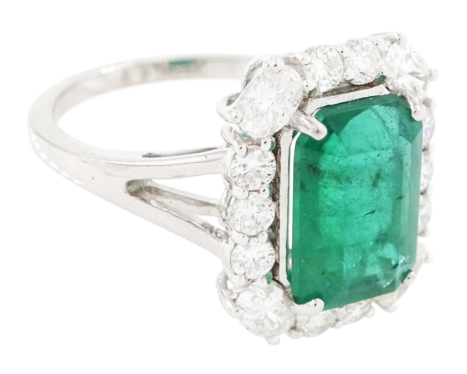 18ct white gold emerald and diamond cluster ring, single octagonal cut emerald of approx 2.90 carat, surrounded by twelve round brilliant cut diamonds and four oval cut diamonds to each corner, stamped 18K, total diamond weight approx 0.90 carat