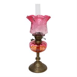 Victorian oil lamp, the brass base supporting cranberry glass reservoir, with clear glass ...