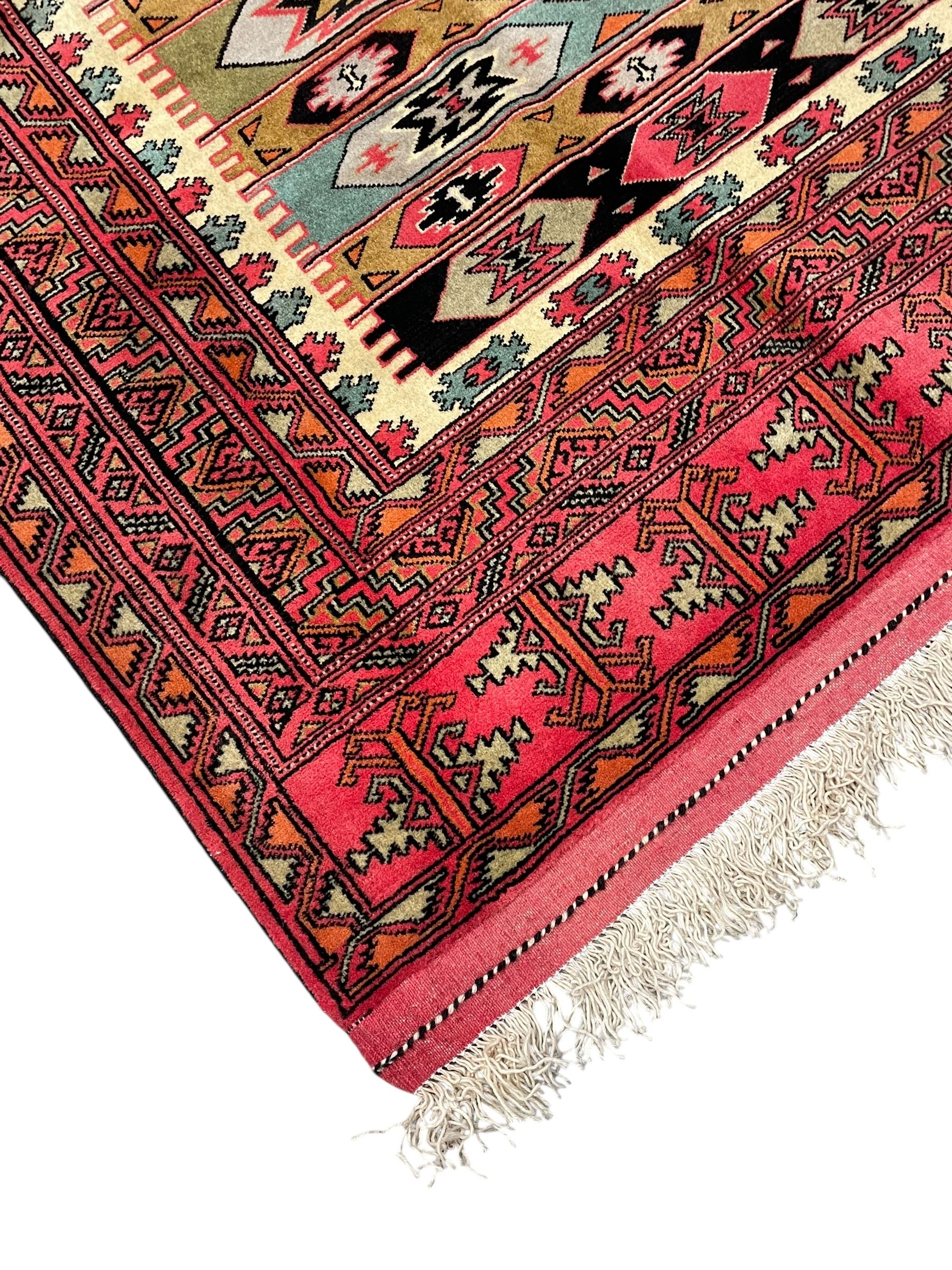 Turkaman red ground rug, the field divided into horizontal rows and decorated with geometric motifs, intricately pattern borders and end panels