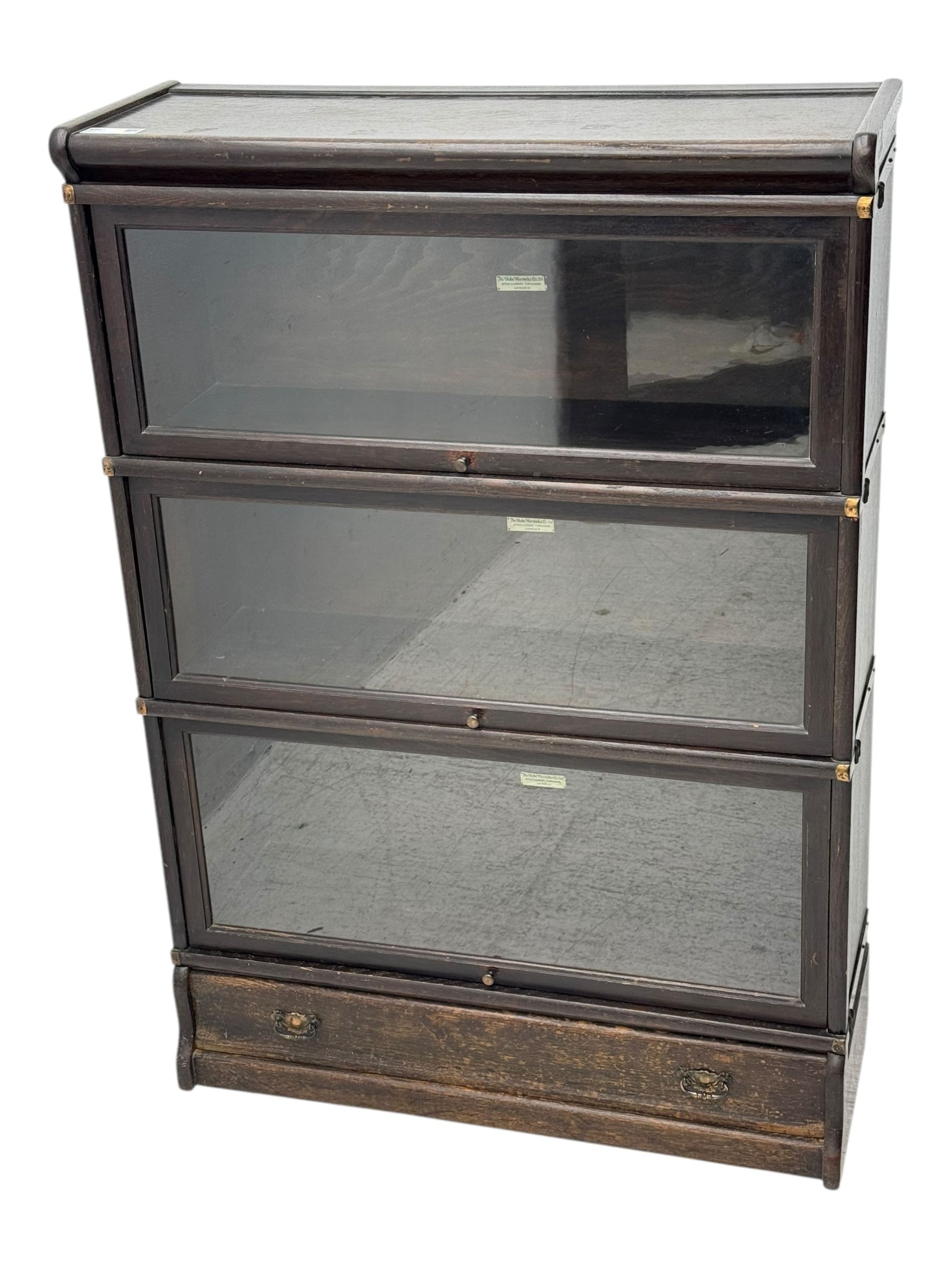 Globe Wernicke - early 20th century oak three-tier stacking library bookcase, three glazed sections enclosed by hinged and sliding doors, raised above a single lower drawer with metal drop handles