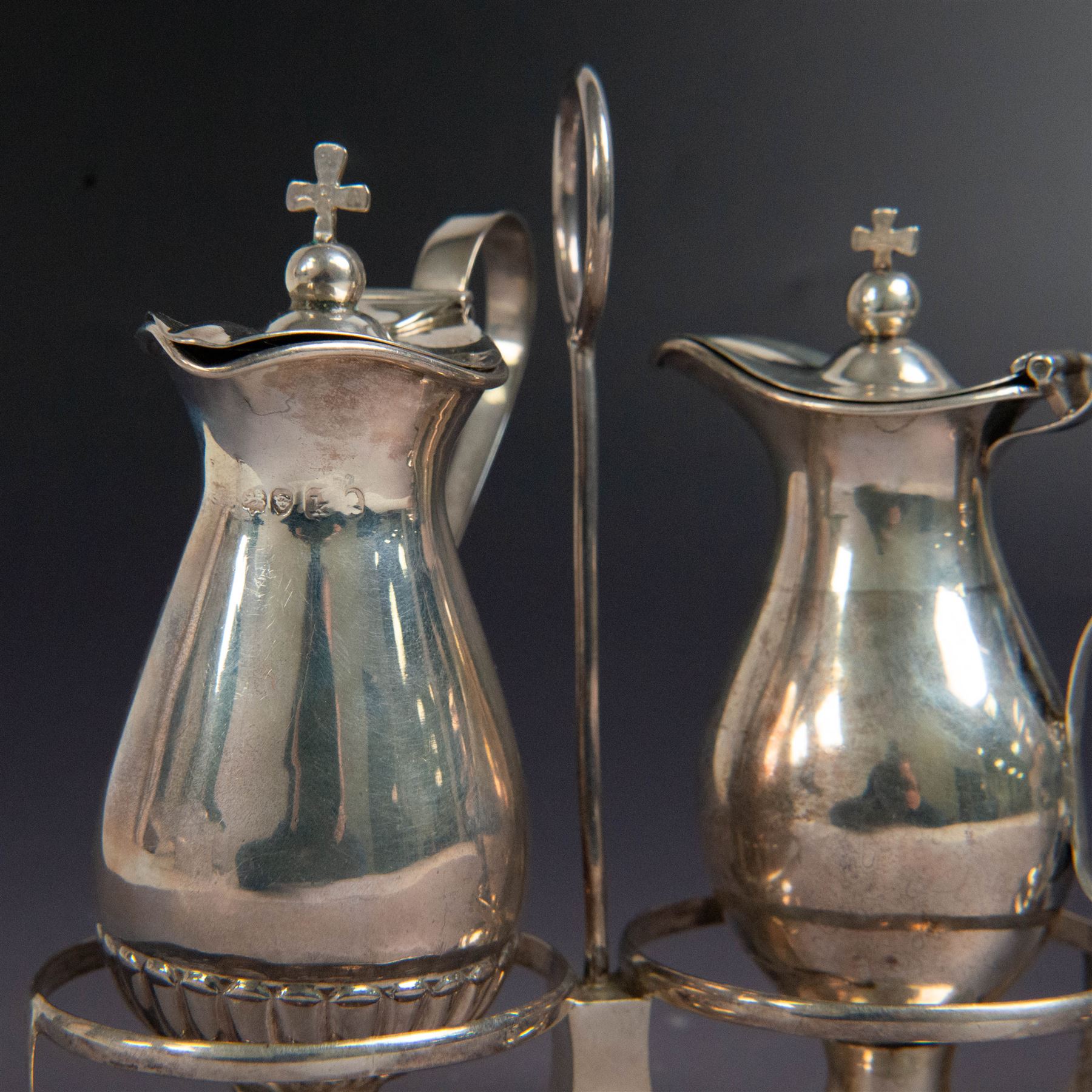 Ecclesiastical silver cruets, comprising two jugs in the form of miniature wine carafes, one hallmarked London 1825, the other unmarked, contained in a silver cruet stand with loop handle, hallmarked London 1937, and a French silver jar and cover in the form of a miniature chalice, with Minerva's head standard mark, tallest H13cm