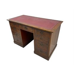 Late 19th to early 20th century walnut pedestal desk, rectangular top inset with red tooled leather writing surface, over a central frieze drawer flanked by two pedestals, each fitted with four graduated drawers with brass escutcheons and drop handles, the whole raised on a plinth base
