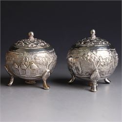 Pair of Middle Eastern silver cruets, of spherical form with pierced tops, embossed with figures, elephants and village scenes, unmarked, together with a pair of silver condiment spoons embossed with floral decoration 