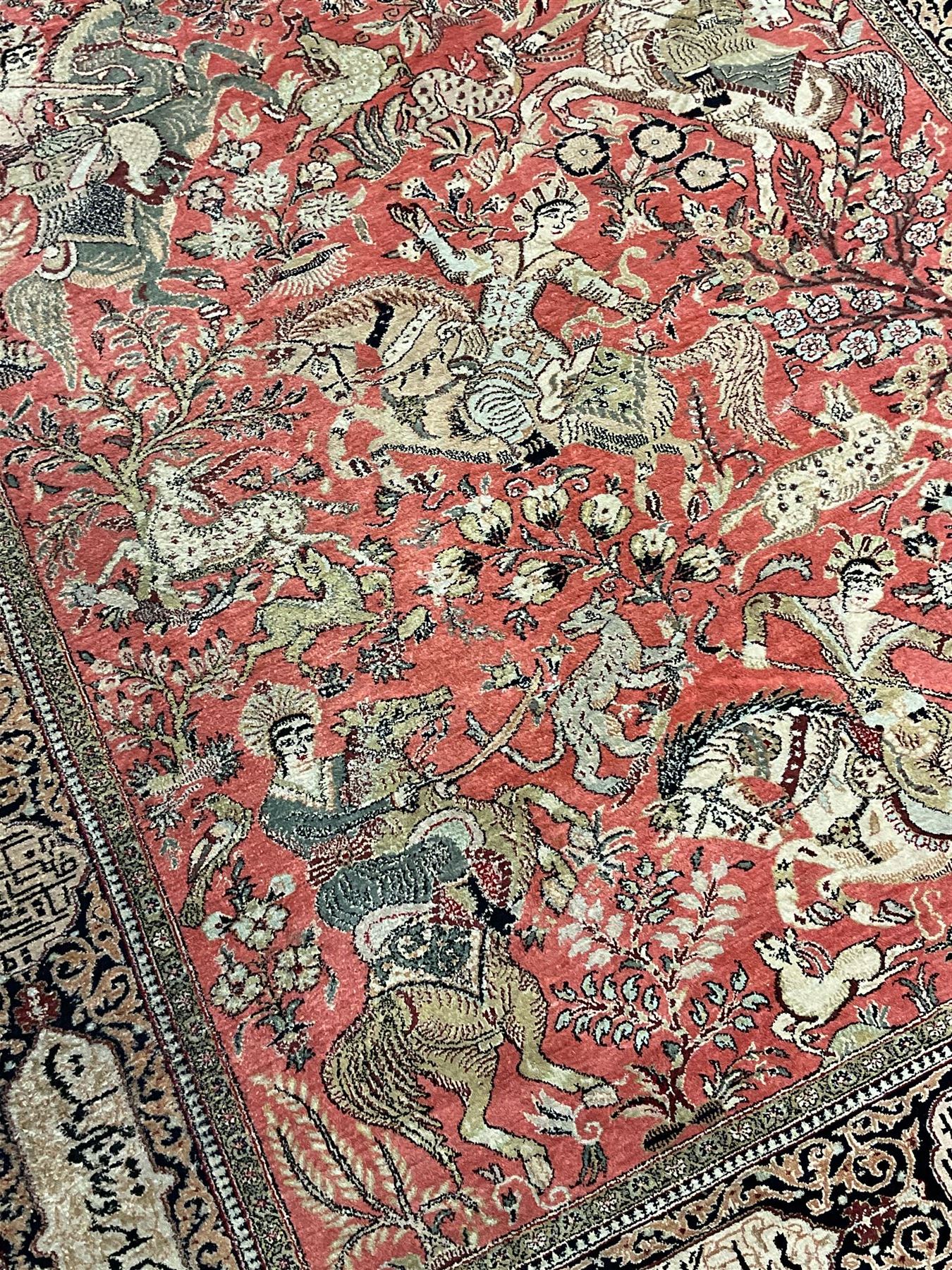 Fine Persian silk and cotton hunting rug, pink ground field depicting hunting scenes, trees and flowers, the border decorated with scrolls and script panel