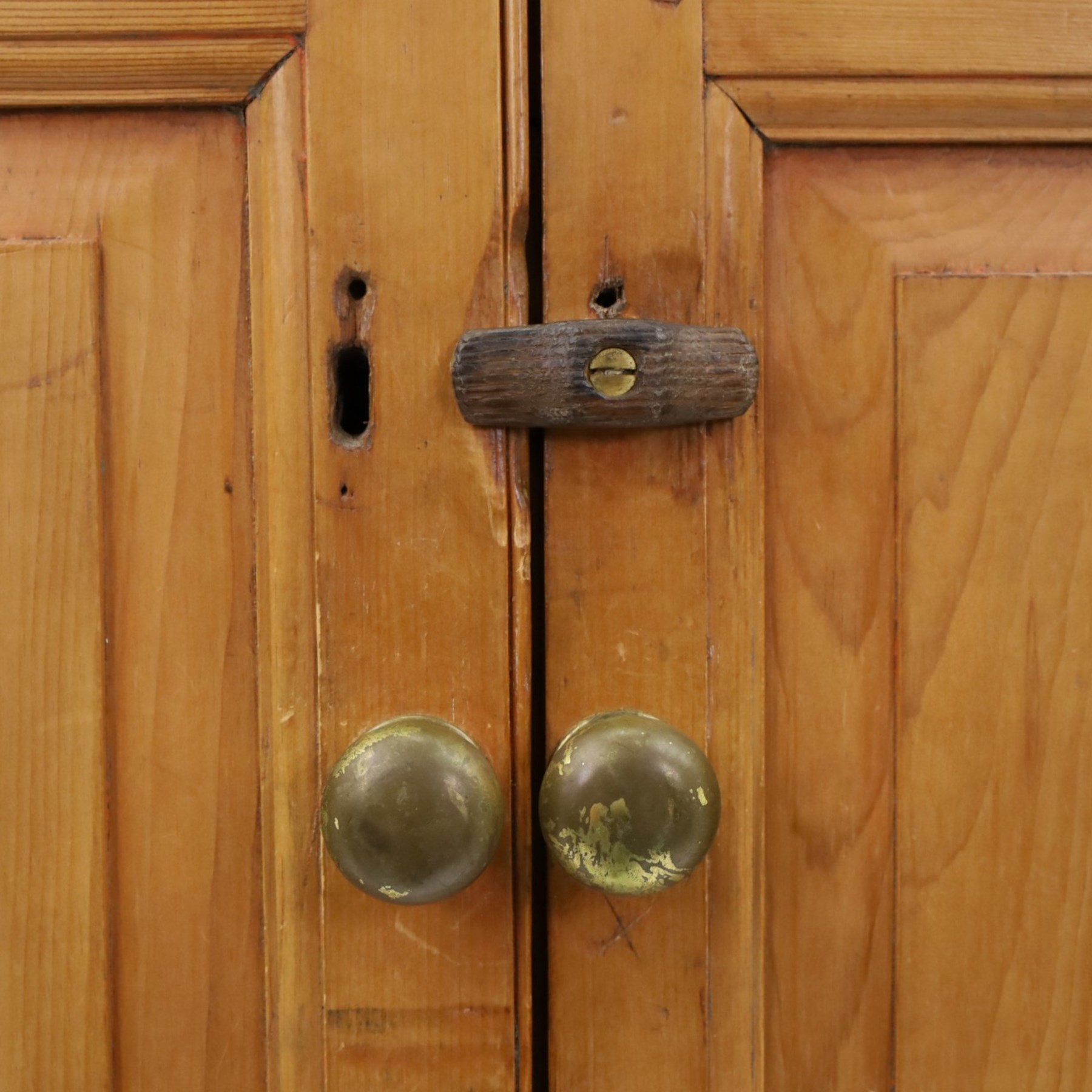 19th century waxed pine press cupboard, shaped cornice above a twin fielded panelled cupboard door enclosing a fixed shelf, the lower section two short two long drawer