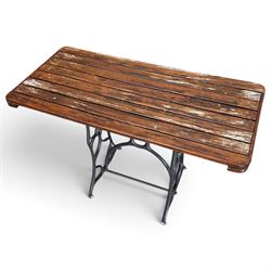 Antique rectangular slatted hardwood garden table, raised on pierced black painted cast iron supports cast with scrolling branchwork and united by pierced curved X-stretcher