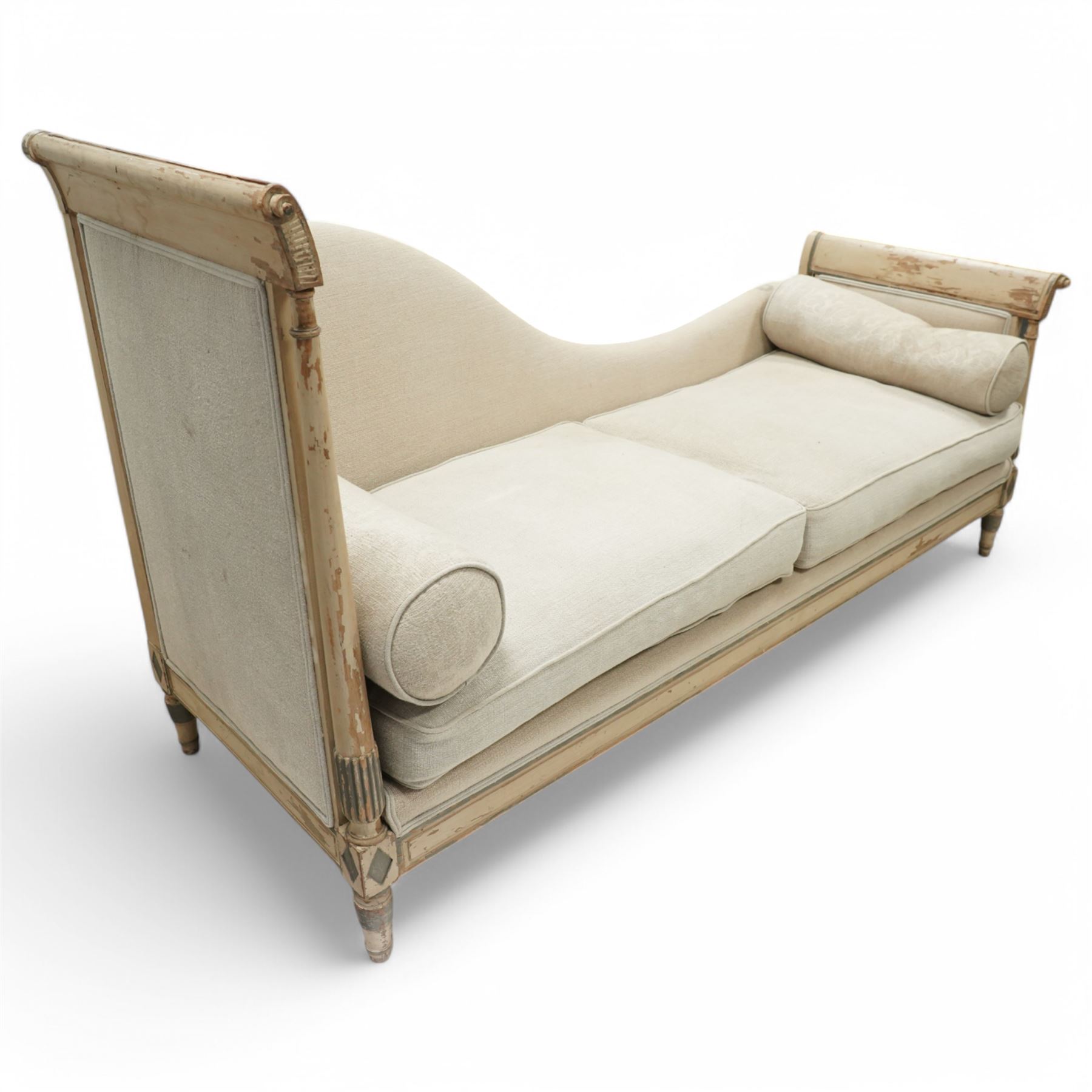 19th Century French day bed, the shaped back and scroll ends with fluted supports and carved rosettes, upholstered in natural linen with loose seat cushions and bolster pillows
