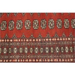 Turkoman hand-knotted rug, madder red ground with two rows of repeating octagonal guls interspersed with geometric motifs, enclosed by multiple geometric and stylised floral borders, with fringed ends
