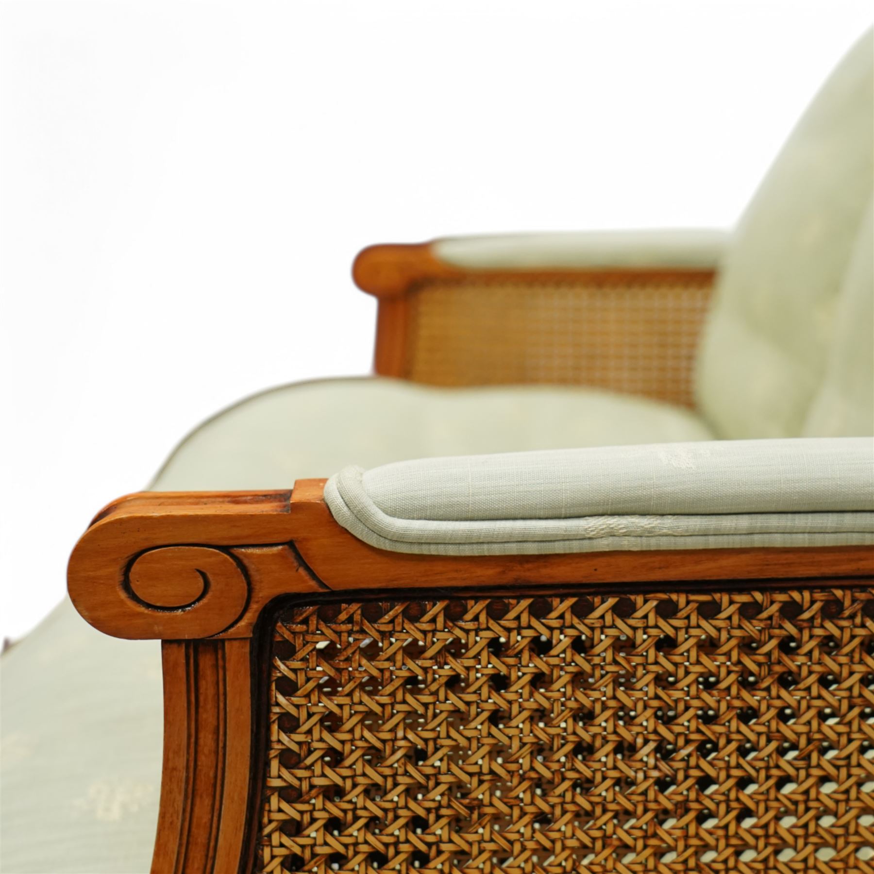 French Empire design varnished wood three piece lounge suite comprising of two cane armchairs and matching sofa, carved top rails with foliate terminals, cane side panels and padded scroll arms, upholstered in a green brocade with matching piping, on fluted legs