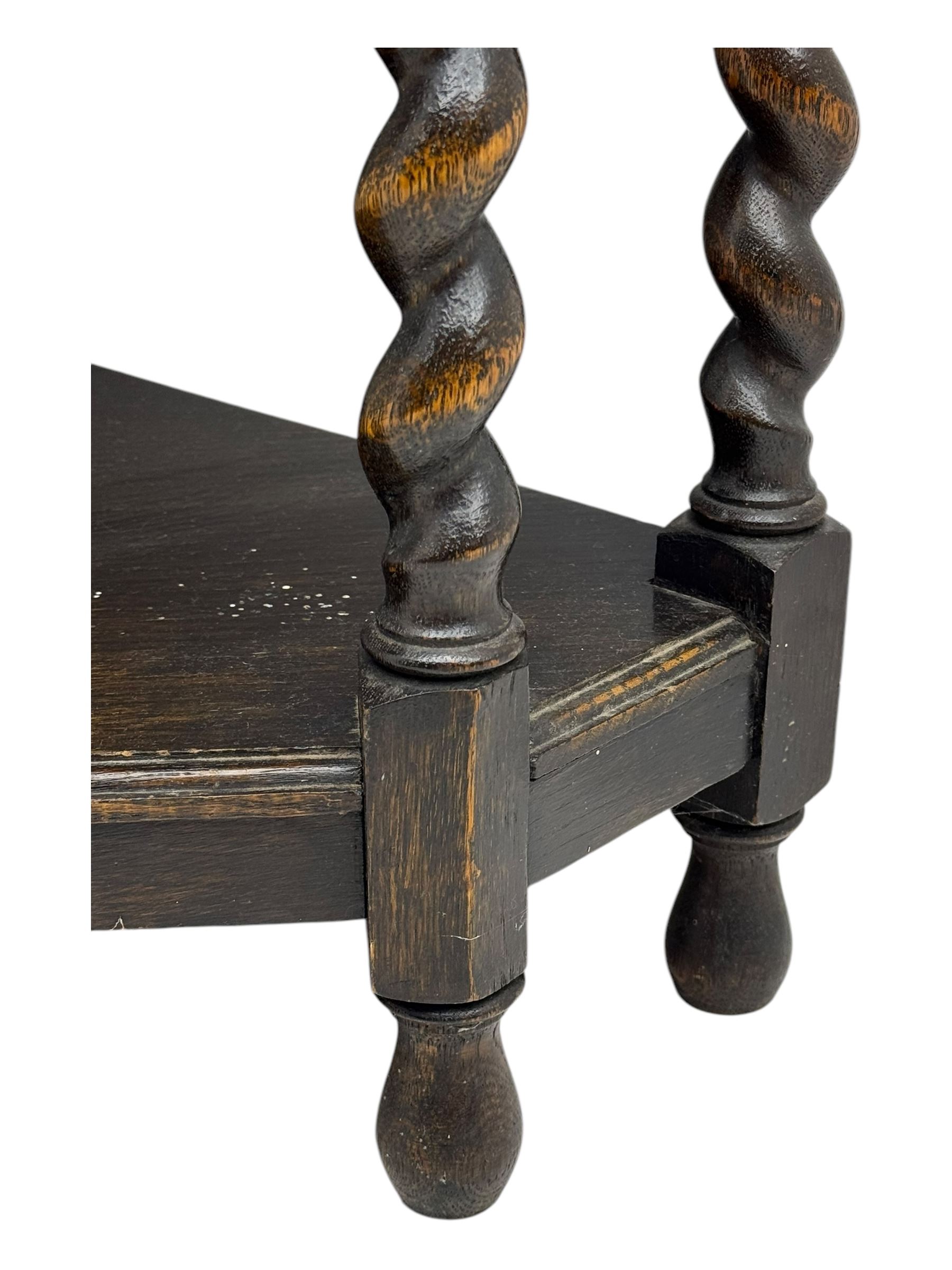 Early 20th century oak corner display cabinet, the moulded canted cornice over a single glazed door with geometric astragal bars, shelved interior, the lower tier forming a triangular platform, raised on four barley-twist supports united by shaped brackets