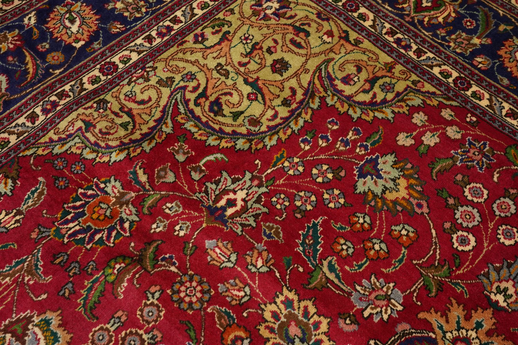 North East Persian Meshad hand-knotted carpet, crimson field with central lobed medallion in tones of indigo, ivory and soft blue, with an all-over arrangement of scrolling vinery, palmettes, and floral  sprays, conforming spandrels, main border of stylized floral vinery framed by multiple guard borders, with cotton fringe ends