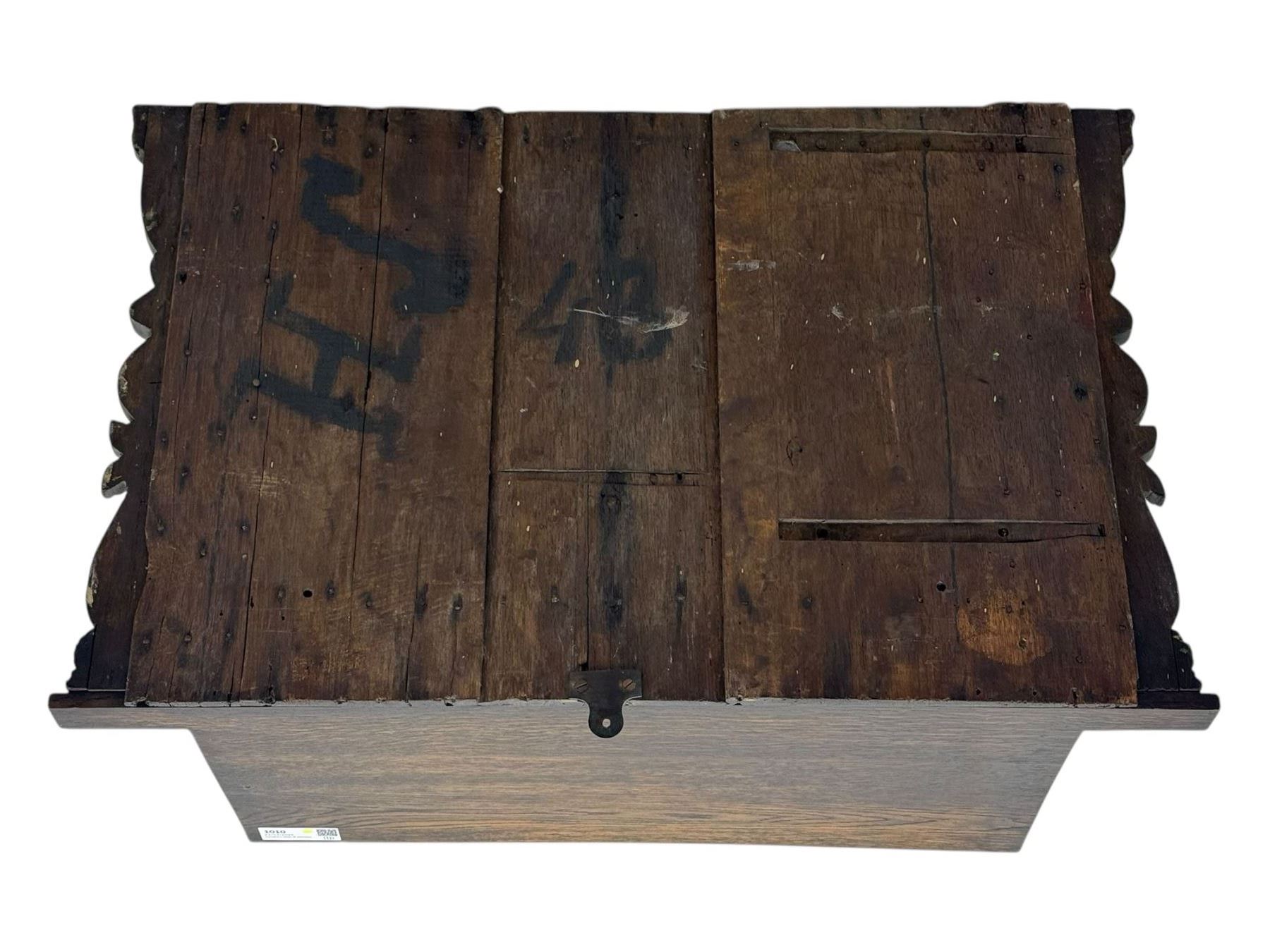 18th century and later carved oak cupboard, enclosed by panelled door carved with central bird motif and scrolled leafage with an outer ebony band, the frieze and uprights carved with repeating lunette and floral designs, flanked by scrolled foliate carved upright brackets