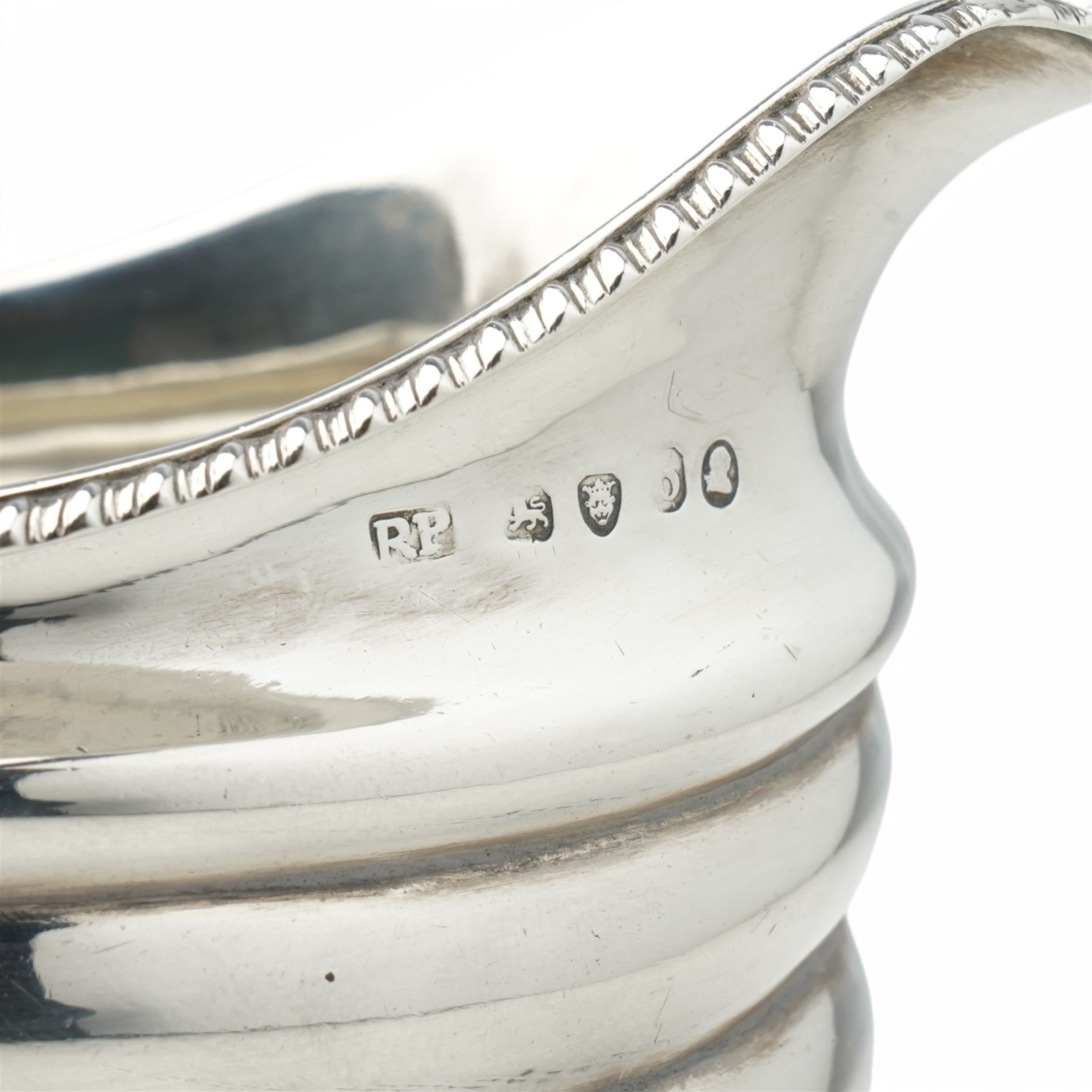 George III silver cream jug with gadrooned edge and leaf capped handle on shaped supports London 1817 Maker Robert Peppin and a small Victorian silver sauce boat with crimped rim Birmingham 1893 Maker Thomas Hayes (2)