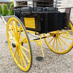 J. W. Thompson Dog Cart

A black and yellow painted two wheeled dog cart with elevated upholstered seat for two, buttoned black leather cushions, high back rail, folding front footboard, louvred sides, side steps, rear drop-down tailboard with chain stays, internal storage compartment, wooden spoked wheels, rubber tyres and shafts for a single horse. The wheel hubs are marked J W Thompson

Dimensions:
Overall length: 366 cm
Width: 160 cm
Height: 190 cm

Wheel Diameter:
Wheels: 139 cm

Seating:
Driver and passenger: 2