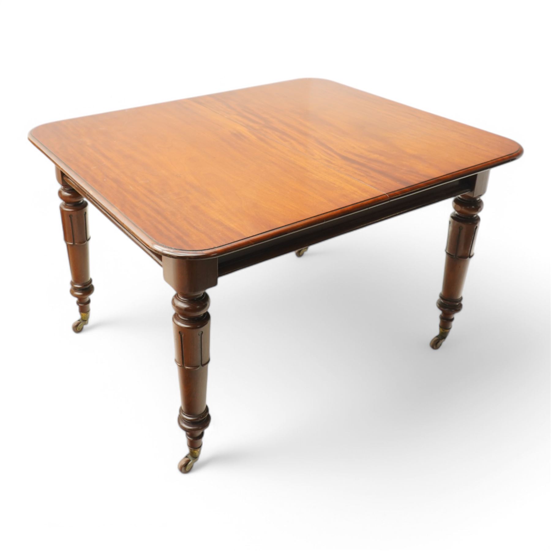 Victorian mahogany extending dining table, moulded rectangular top with rounded corners, pull-out action with additional leaf, on turned and lappet carved supports terminating to brass and ceramic castors 