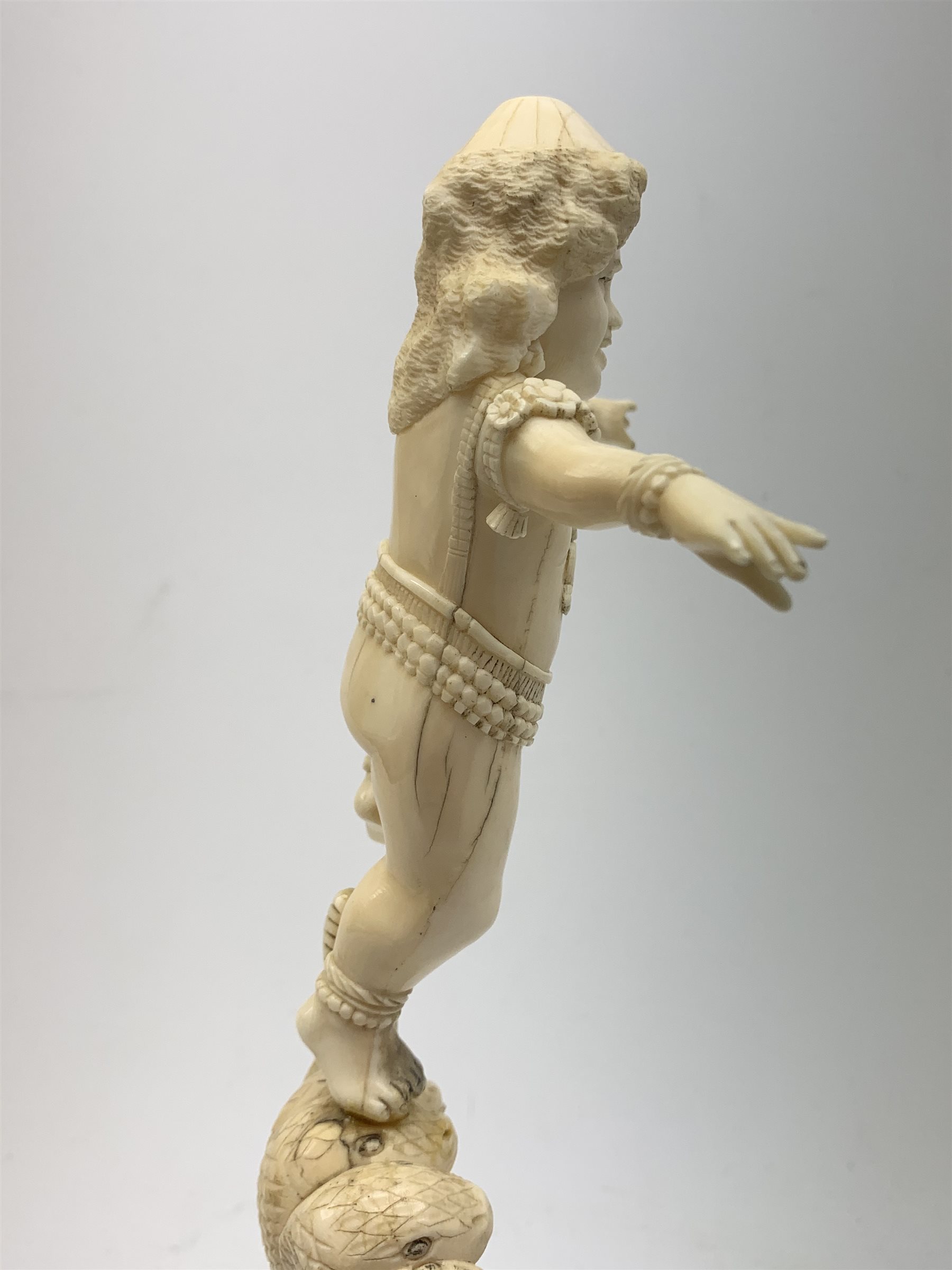 A large Japanese carved ivory okimono, modelled as a figure stood upon one leg with arms outstretched, upon a five headed serpent emerging from waves, H30cm.