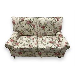 Steed Upholstery - 'Knightsbridge' two seater sofa, upholstered in cream fabric with pink and green floral design, loose back and seat cushions, raised on mahogany supports with brass castors