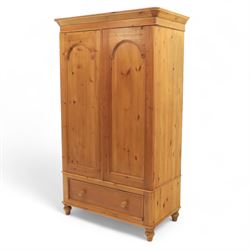 Two contemporary traditional-style wardrobes, projecting plain cornice above two arched moulded panel doors, above a full-width drawer fitted with turned wooden handles, raised on turned bun feet