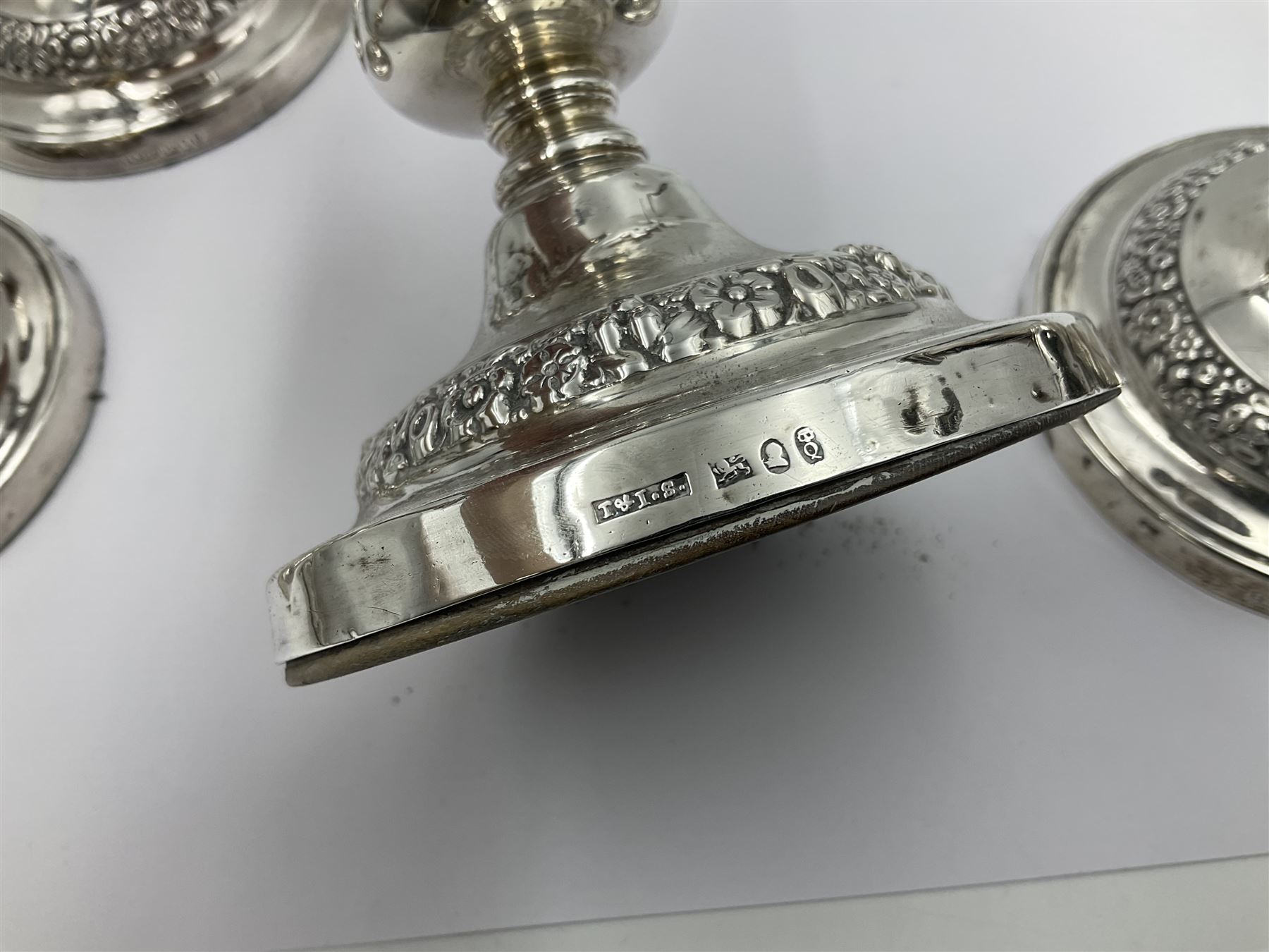 Four George III silver candlesticks, each upon knopped stem and weighted circular stepped foot, the foot and removable sconce repousse decorated with a band of flower heads, hallmarked to sconce and foot Thomas & John Settle, Sheffield 1820, H17.5cm