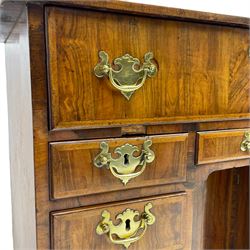 Early 18th century Queen Anne figured walnut kneehole desk with secretaire drawer, moulded and book matched top with walnut band, the top drawer with fall front enclosing small drawers and pigeon holes, fitted with nine drawers and central recessed cupboard, on ogee bracket feet