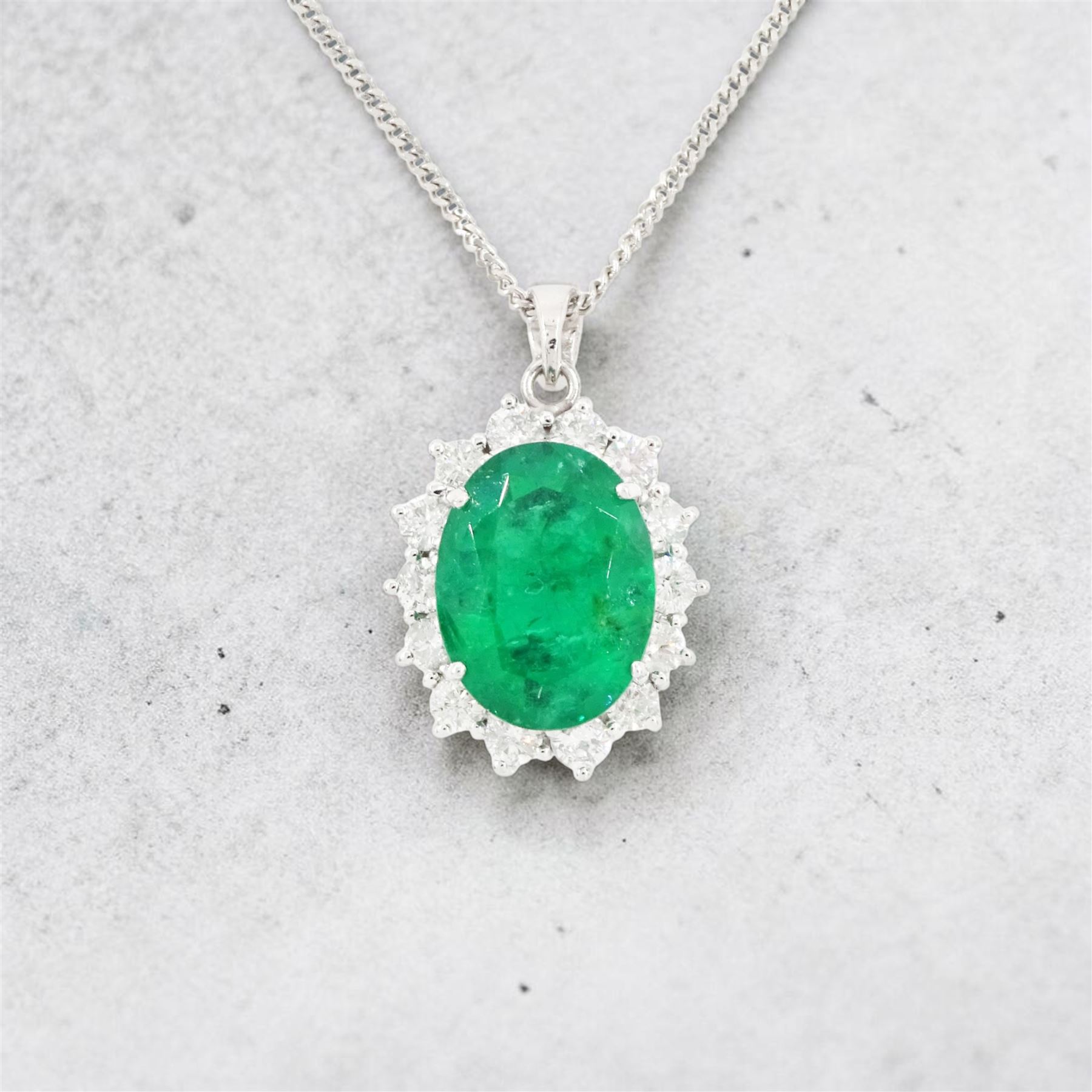 18ct white gold emerald and diamond pendant necklace, single oval cut  emerald of approx 3.25 carat, surrounded by fourteen round brilliant cut diamonds, on a fine link chain necklace, hallmarked, total diamond weight approx 0.50 carat