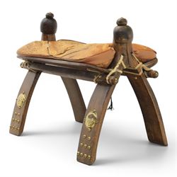20th century Camel stool, with wooden turned finials, above a tooled leather seat, curved supports with brass applications 