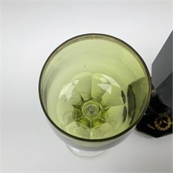 19th Century Bohemian amethyst glass lidded goblet, the bowl of faceted form, gilded with three children in period dress playing games, upon a knopped stem and conforming faceted foot, together with an art nouveau green glass goblet, with gilded rim, upon clear trumpet stem, and a hand blown wine glass, transfer printed with birds and three figures in period dress, tallest H29cm